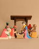 The Ostheimer Nativity Scene - Extended is a handcrafted wooden set, created from sustainable materials, showcasing vibrant figures such as Mary, Joseph, baby Jesus in a manger, the three wise men, a shepherd, and a camel. It's perfect for imaginative play beneath a minimalistic stable backdrop.