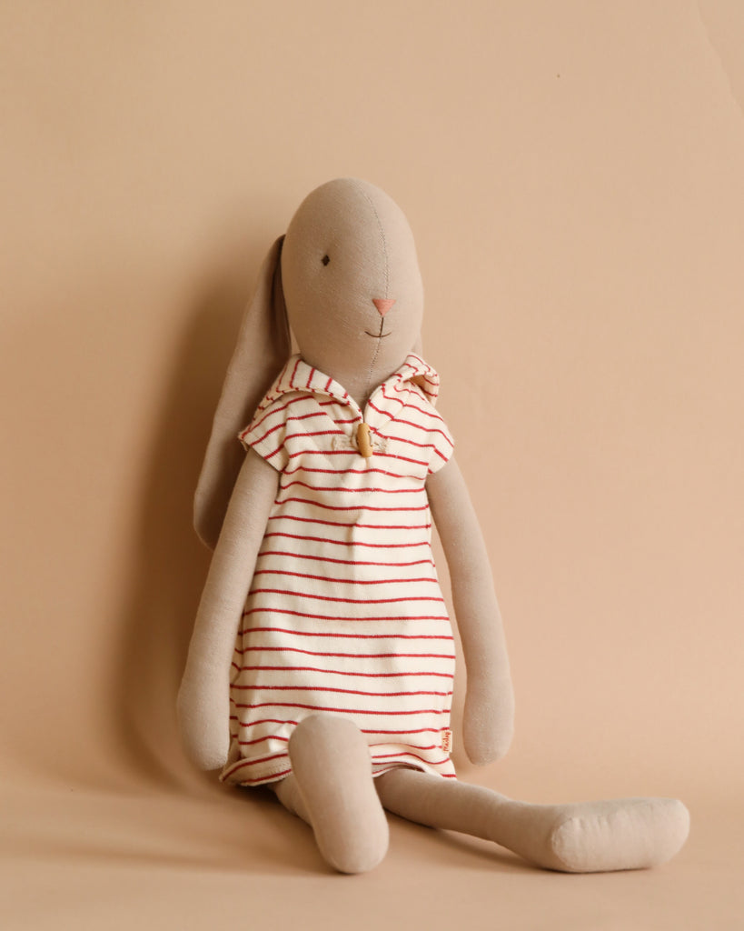 The Maileg Bunny Size 4, dressed in a red and white striped sailor outfit, sits against a beige background, ready for adventure.