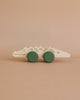 A handmade in Poland wooden toy shaped like a crocodile with simple painted details is displayed against a light brown background. This Wooden Crocodile Push Toy features two large green wheels attached to the bottom, making it perfect for helping toddlers develop fine motor skills.