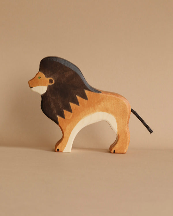 A handcrafted wooden toy lion stands on a neutral background. The Holztiger Lion, part of the renowned HOLZTIGER figures collection, is painted in shades of brown with a dark mane and lighter body. The simple, stylized design highlights the lion’s distinctive features, emphasizing the high quality toys’ craftsmanship.