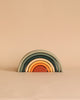 A handmade Mini Rainbow Stacker - Jungle consisting of five arches in earth tones, neatly nested together against a light peach background.