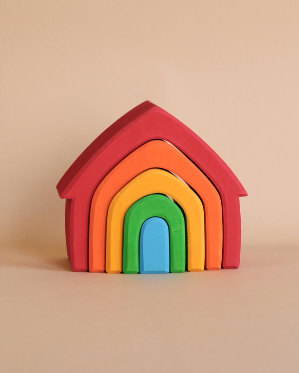 A Grimm's Colorful House Stacker composed of nested arches in red, orange, yellow, green, and blue is centered against a plain beige background. Perfect for toddlers, this non-toxic toy combines vibrant hues and safe playtime fun.