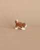 A small, handcrafted figurine of an Ostheimer Small Saint Bernhard Dog - Head Down in a playful stance, isolated against a plain beige background.