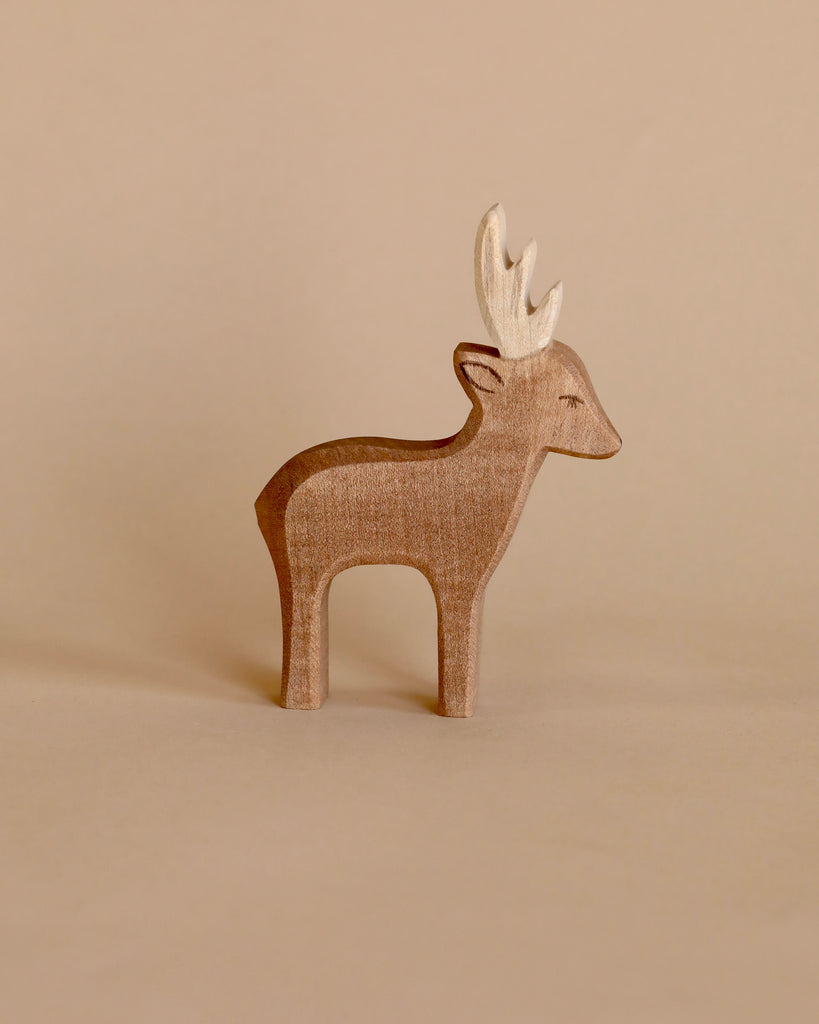 A Ostheimer Deer with prominent antlers, standing against a plain beige background. The figure displays a smooth texture and simplistic design typical of Ostheimer toys.