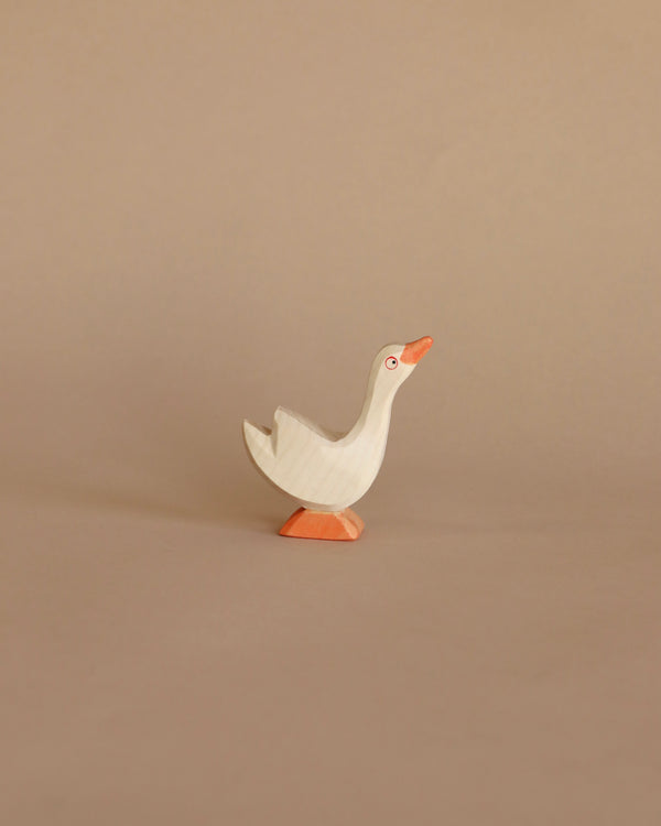 A simple handcrafted Ostheimer Goose - Head Up toy with a white body and orange beak and feet, standing against a plain beige background.