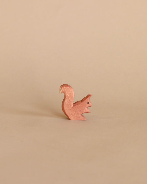 A small, copper-colored Ostheimer Squirrel - Sitting pin stands against a plain light beige background, evoking the imaginative play often inspired by Ostheimer toys.