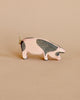 A handcrafted Ostheimer Spotted Pig - Head Low figurine with a simple, stylized design, featuring a pale pink body and gray accents, displayed against a soft beige background.