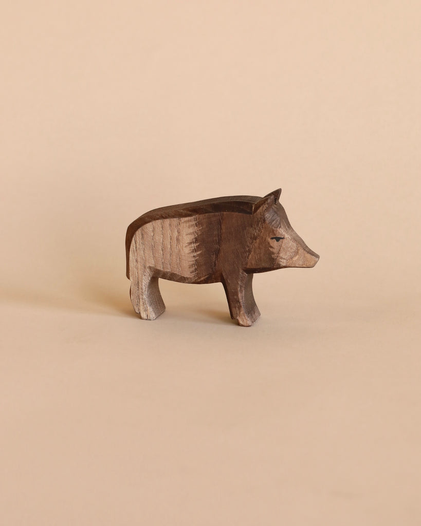 A handcrafted Ostheimer Wild Boar figurine, displayed against a soft beige background, featuring detailed textures and a lifelike pose.