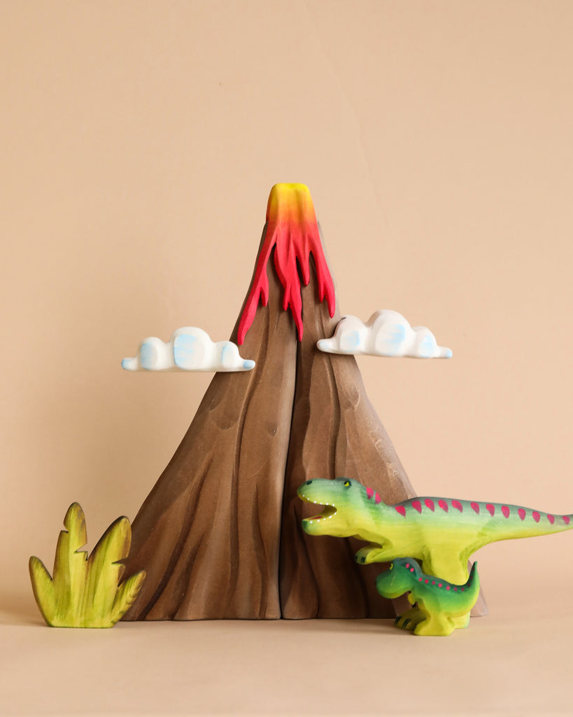 A Handmade Wooden Volcano & Dinosaurs Set depicts a brown volcano with red and yellow lava at the top, all painted with non-toxic paint. Two white clouds float on the sides of the volcano. A green and purple dinosaur stands on the right side, and a green bush is on the left, all set against a beige background.