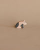 A handcrafted Ostheimer Spotted Piglet - Sitting with black and white painted details, positioned against a plain beige background.