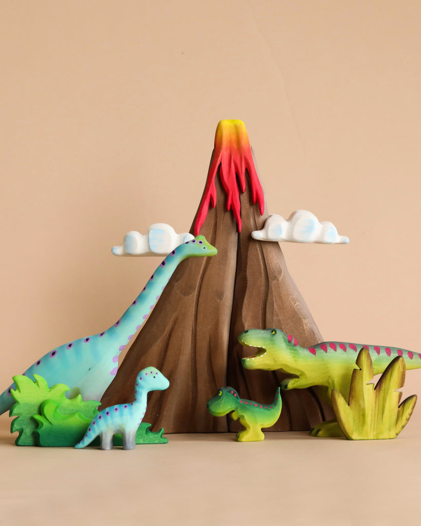 A Handmade Wooden Volcano & Dinosaurs Set from Romania, including a long-necked dinosaur, a T-Rex, and two smaller ones, are arranged around a toy volcano with red lava flowing from the top. The background is beige, and there are fluffy white clouds around the volcano. Made with non-toxic paint for safe play.