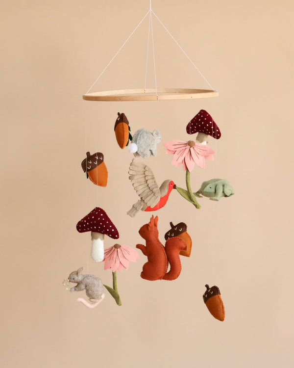 A Handmade Mobile - Forest Friends - Final Sale featuring felt figures of woodland animals and flora, including a rabbit, squirrel, bird, and mushrooms, hanging against a soft beige background.