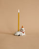 A whimsical heirloom-quality Goat Cake Topper featuring a smiling white sheep wearing a red scarf and a party hat, with a tall, lit yellow birthday candle sticking up from its back. The background is a