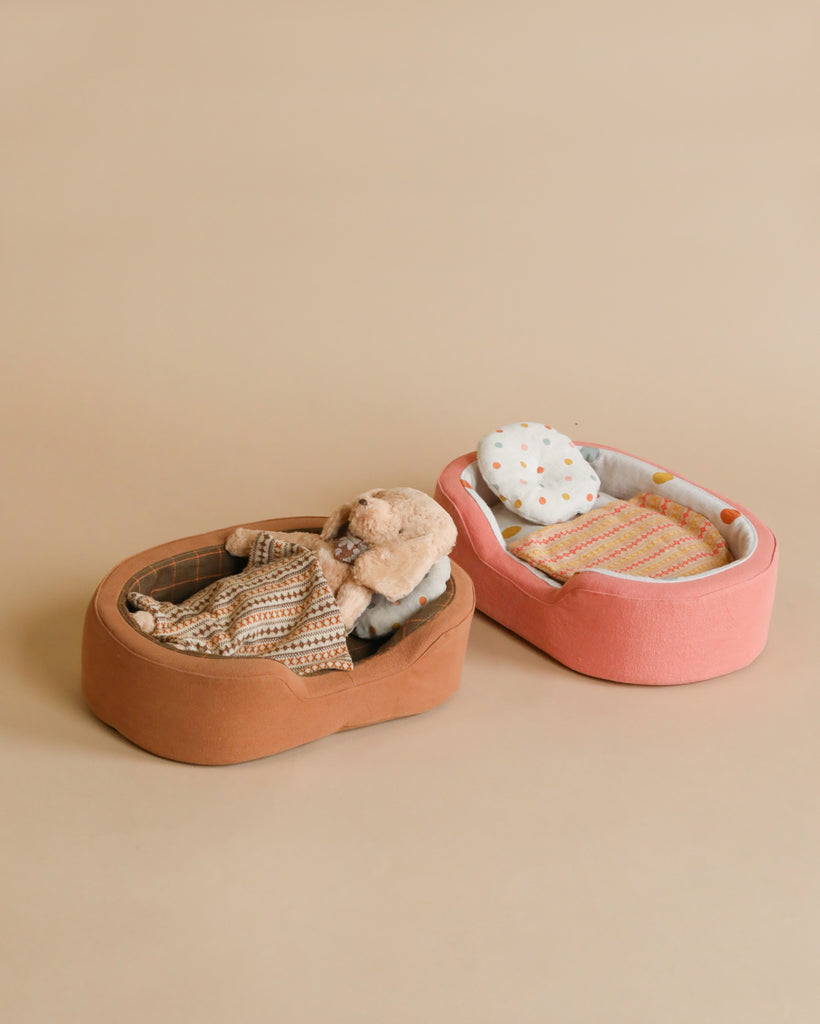 A photo featuring two toy dog beds with a a toy dog laying in one of the beds.