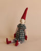 The Maileg Christmas Mini Pixy (Size 2), a fabric doll featuring a cheerful face, is dressed in a green checkered dress along with red gloves, socks, and hat. It sits against a neutral background. Crafted from exclusive materials, the doll has striped arms and legs with curly hair peeking out from under the pointed hat—perfect as a Christmas decoration.
