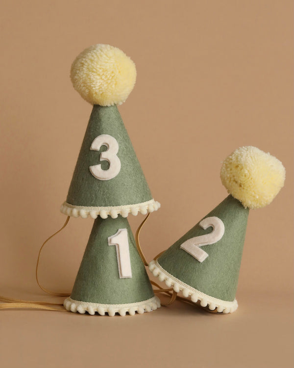 Three Olive Party Hats made of green felt with white pompoms on top and white trim at the base are displayed against a plain background. Each hat features a bold white number: 1, 2, and 3. Perfect for birthday celebrations or photo shoots, a golden string is attached to secure the hats under the chin.