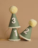 Three Olive Party Hats made of green felt with white pompoms on top and white trim at the base are displayed against a plain background. Each hat features a bold white number: 1, 2, and 3. Perfect for birthday celebrations or photo shoots, a golden string is attached to secure the hats under the chin.