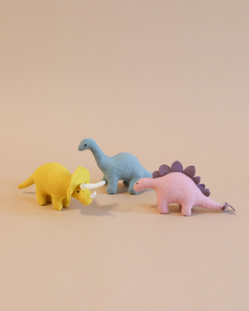 three stuffed dinosaur toys standing.