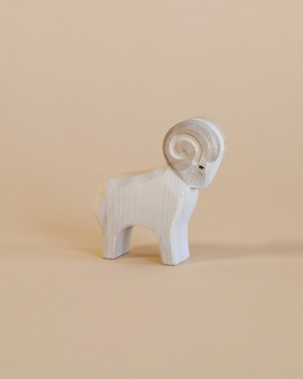 A small Ostheimer Ram figurine with a prominent spiral horn and detailed carving, standing against a plain beige background.