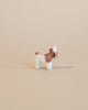 A small handcrafted Ostheimer Goat Kid - Standing with a brown body and white face and legs, standing against a plain beige background.