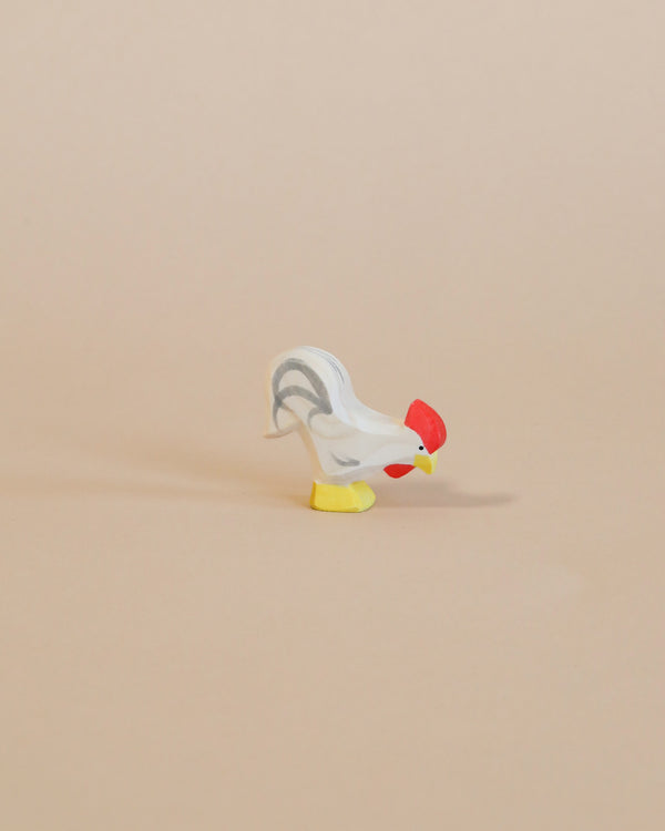 A small handcrafted Ostheimer Rooster - White with a red head and yellow feet positioned on a plain beige background.