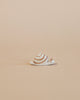 A small handcrafted Ostheimer Snail figurine with spiraled shell patterns, positioned on a plain beige background.