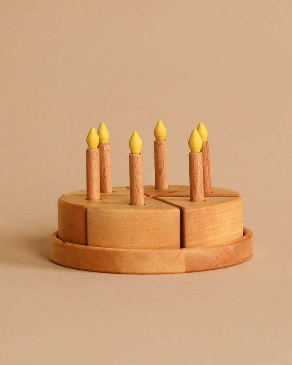 Introducing our "Handmade Wooden Birthday Cake," a charming round candle holder crafted from smooth, light-colored pear wood. It features seven upright wooden candles topped with small yellow flames. Lovingly handcrafted in Ukraine, this delightful set is finished with linseed oil and beautifully presented against a beige background.