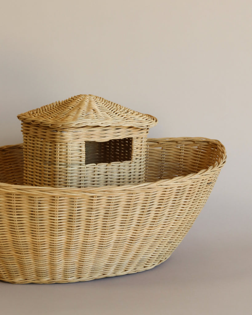 A Braided Ark shaped like a boat, featuring intricate weaving and a raised cabin-like structure, set against a plain, light-colored background.