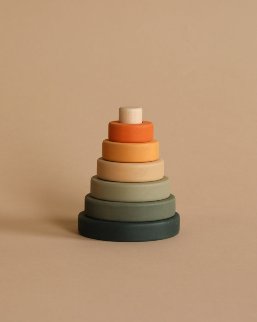 The Mini Wooden Pyramid Stacker - Jungle by Sabo Concept is a minimalist, pastel-colored toy pyramid featuring six differently colored, disc-shaped rings arranged in increasing diameter from top to bottom. This handmade stacking toy is crafted with non-toxic paint and sits elegantly against a plain beige background.