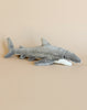 A Great White Shark Stuffed Animal with realistic features and a white underside, resting against a beige background.