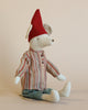 A handmade stuffed mouse wearing cozy Christmas clothes, teal pants, and a red pointed hat, sitting against a plain light background.