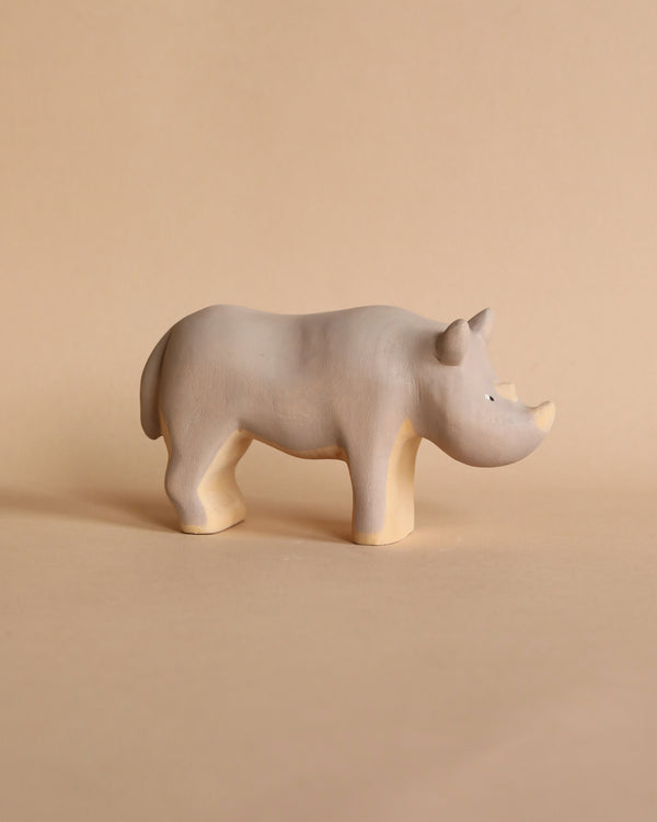 A Handmade Wooden Rhinoceros, handcrafted from linden wood by Meshka and Friends, with a simple, smooth design and minimalistic features stands on a light beige background. Painted with non-toxic paint, it is both safe and charming.