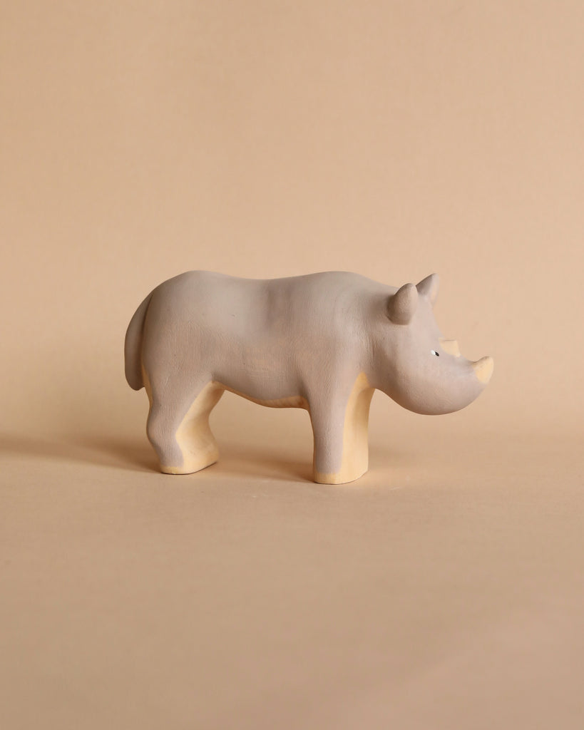 A Handmade Wooden Rhinoceros, handcrafted from linden wood by Meshka and Friends, with a simple, smooth design and minimalistic features stands on a light beige background. Painted with non-toxic paint, it is both safe and charming.