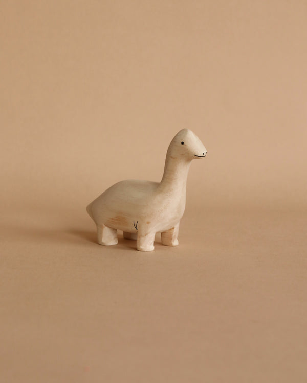 A Handmade Tiny Wooden Brachiosaurus with a simple design and a smiling face, standing on a plain beige background.