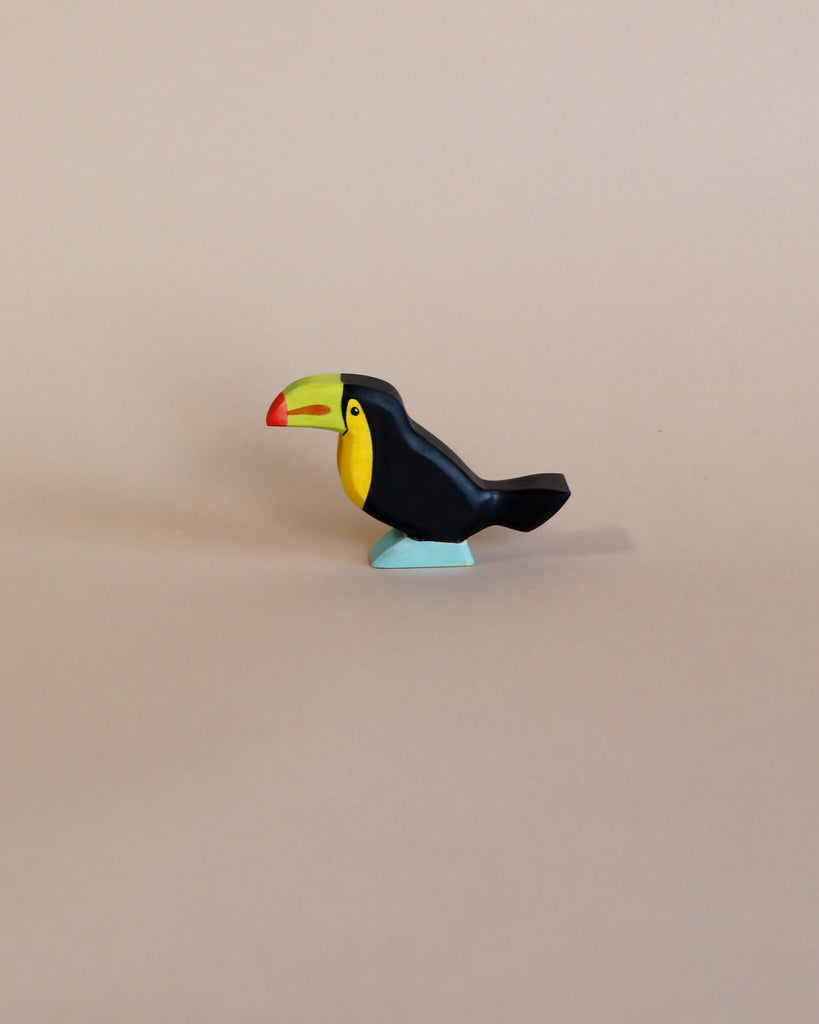 A colorful, high-quality Handmade Holzwald Toucan Bird toy with a prominent red and yellow beak and dark blue body, positioned against a plain light beige background.