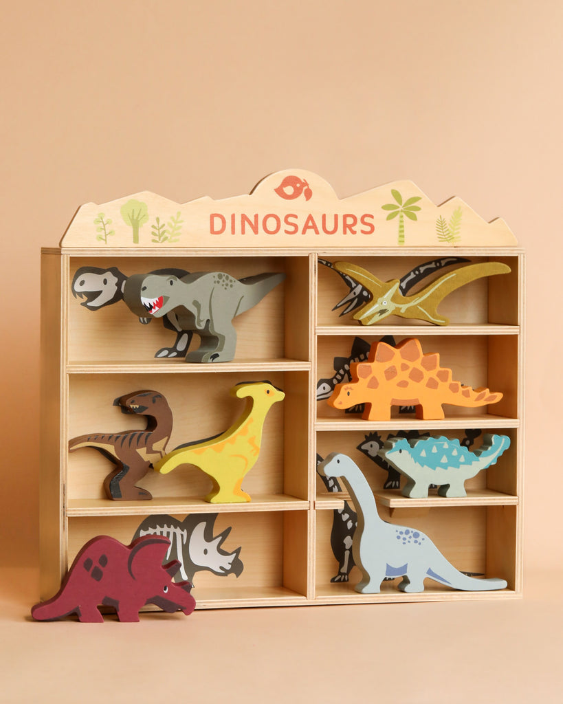 Wooden display shelf labeled "Dinosaurs Set" containing colorful sustainably sourced toys in various poses, set against a plain beige background.