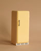 The Maileg Miniature Fridge - Yellow is a small, vintage-style refrigerator specially designed for a miniature dollhouse. It features the brand name "Maileg" elegantly inscribed on the door, along with a single handle, bottom ventilation, and a convenient magnetic closure. This charming little fridge is set against a plain beige background.