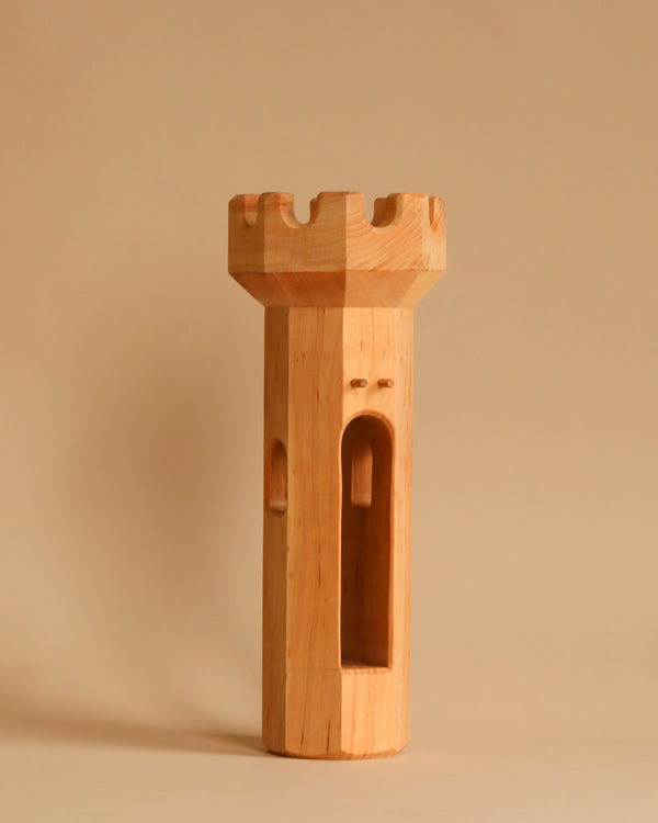 An Ostheimer Round Tower stands upright on a beige background, featuring a crenellated top and a smooth, curved body with an arched window-like design on one side. This handcrafted wooden piece embodies the charm of toys perfect for imaginative play.