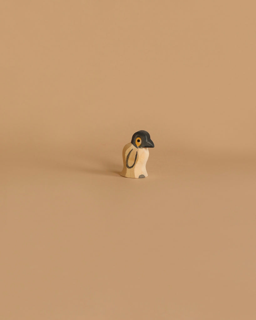 The Ostheimer Penguin, Small is a minimalist wooden figurine featuring a black head and white body. This handcrafted toy stands alone against a beige background, characterized by its simplicity and modern aesthetic. With minimal details, it offers a clean design that’s perfect for imaginative play.