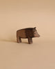 A small, wooden carved pig stands on a beige background. This Ostheimer Wild Boar features a simple, minimalist design with smooth surfaces and subtle carving details, giving it a rustic, handcrafted appearance perfect for imaginative play. Resembling other Ostheimer wooden toys, it evokes the charm of handcrafted toys from yesteryear.