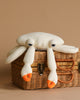 A BigStuffed Mini Crab - Sir plush with white coloring and orange-tipped claws sits on a woven basket against a neutral beige background. The crab has large, droopy eyes and a soft, textured appearance, giving it a cute and cuddly look perfect for newborns.