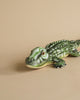 A realistic plush model of an Alligator Stuffed Animal resting on a plain beige background.