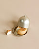 A partially eaten Maileg Cheese Bell, a delicious surprise, rests on a small plate with a silver cloche cover. A piece of the sweet treat lies beside the plate on a light beige surface, almost as if tempting someone—perhaps even the household mice—to indulge.