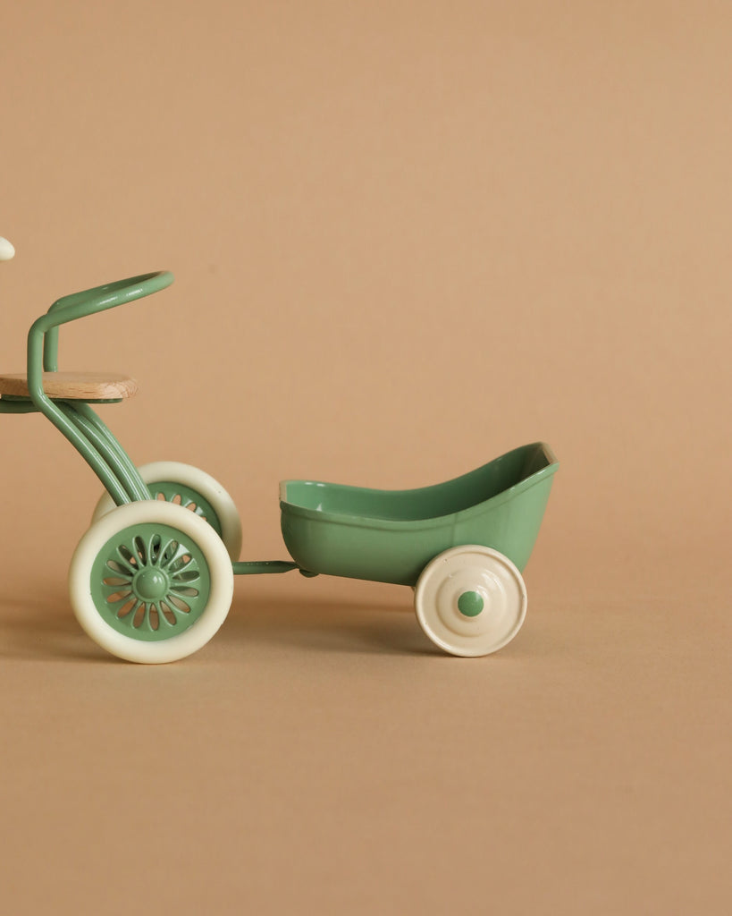 A Maileg Tricycle Hanger, Mouse - Green with a small hanger attached, set against a plain beige background. The toy features intricate wheel designs and a smooth finish.