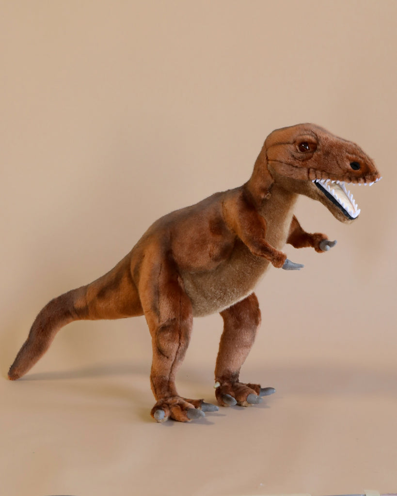 A T-Rex Stuffed Animal standing against a plain beige background, featuring detailed stitching and a realistic design with sharp white teeth and focused eyes. This artisan hand-sewn figure captures the