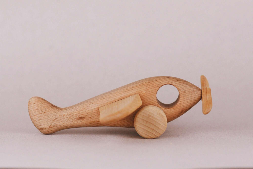 Introducing the Handmade Wooden Airplane, a charming and expertly crafted toy with gently curved edges. This delightful plane includes circular wheels and a petite propeller at its front. Finished with natural linseed oil, the wood grain elegantly stands out against a subtle backdrop.