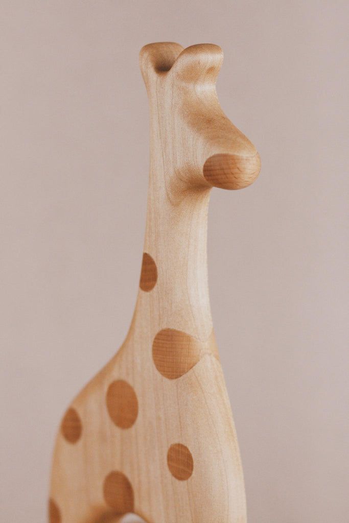 Introducing the Handmade Wooden Giraffe Pull Toy: a beautifully crafted giraffe figurine made from smooth, light wood. This minimalist design features darker circular spots on its body, defined curves, and is set against a plain background, making it an appealing addition to any child's toy collection.