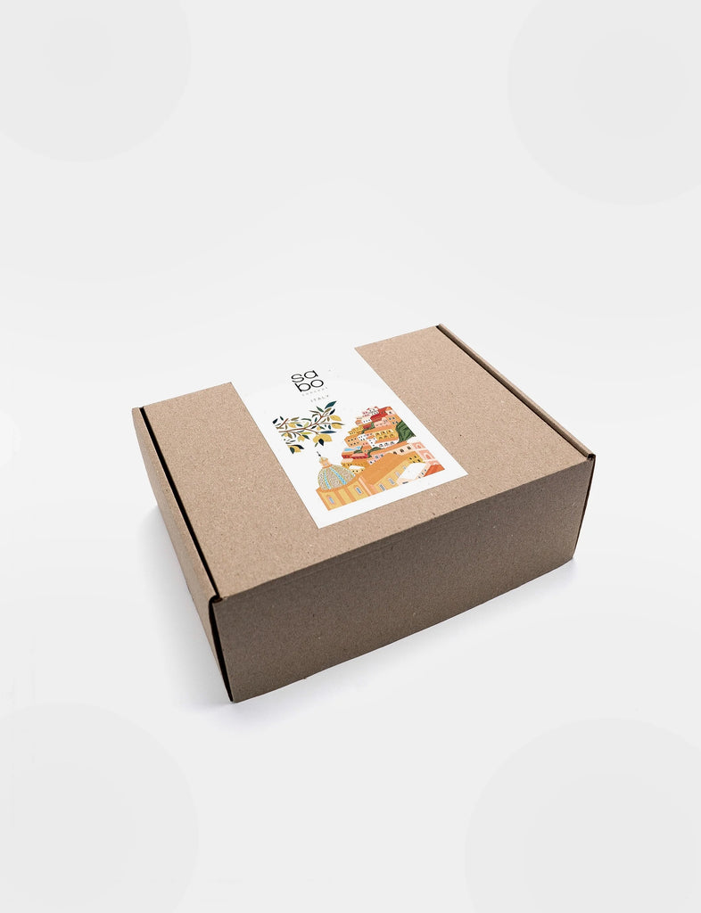 A closed rectangular brown cardboard box with a decorative shipping label featuring colorful illustrations of plants and Sabo Concept Italian Courtyard Blocks, viewed against a plain white background.