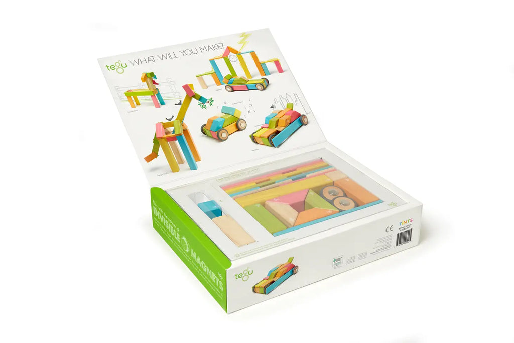 An open box of the Tegu 42 Piece Magnetic Wooden Block Set - Sunset displaying colorful wooden sticks, magnetic wheels, and example projects like a unicorn and cars, with the text "what will you make?" on the inside cover.