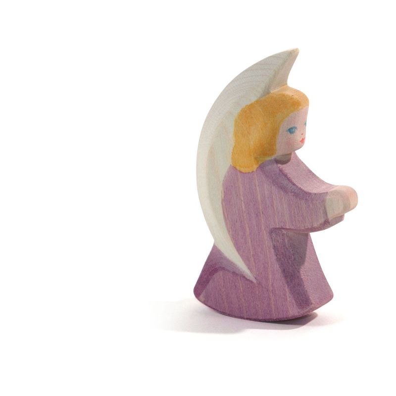 The Ostheimer Little Angel - Purple is a handcrafted wooden figurine depicting an angel with light brown hair, dressed in a lilac robe, holding a crescent moon behind its back. Made from sustainably sourced materials, this minimalist piece evokes the enduring charm of Ostheimer wooden toys and is beautifully set against a white background.